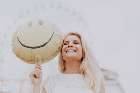vrouw-die-lacht-met-smiley-ballon
